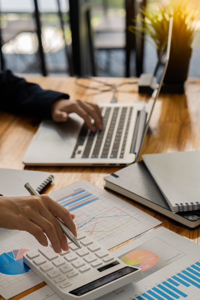 An accountant uses a calculator and computer while sticking to the concept of business accounting. Budget and Loan Hands of people making money and calculating expenses at the office vertical picture computer laptop