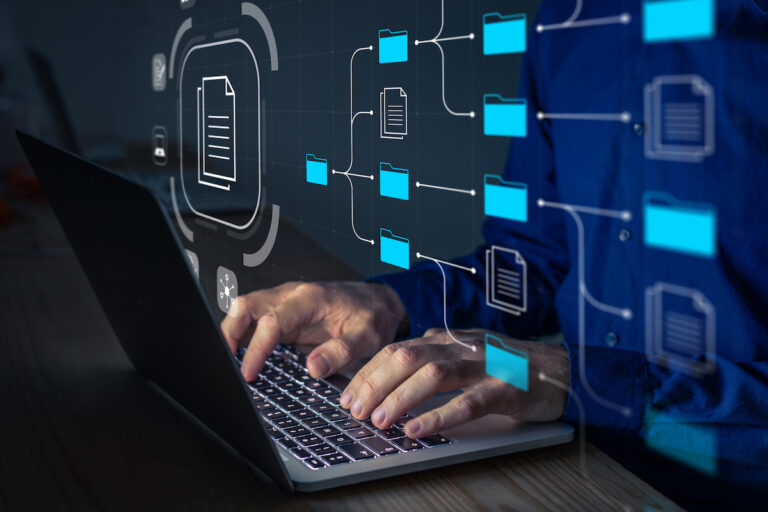 Document Management System (DMS) being setup by IT consultant working on laptop computer in office. Software for archiving, searching and managing corporate files and information. Business processes computer laptop and typing