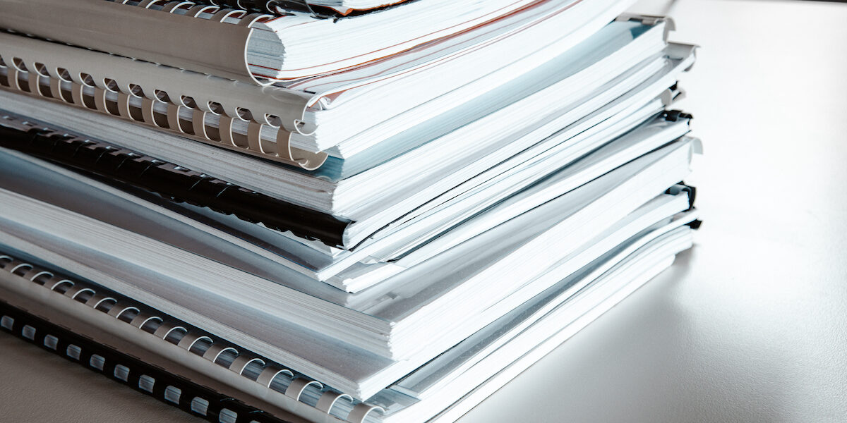 Stack of reports lies on a desk ready for review binders of reports