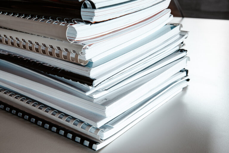 Stack of reports lies on a desk ready for review binders of reports